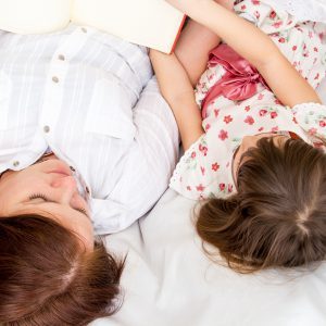 A mother and her little daughter reading a book before sleeping